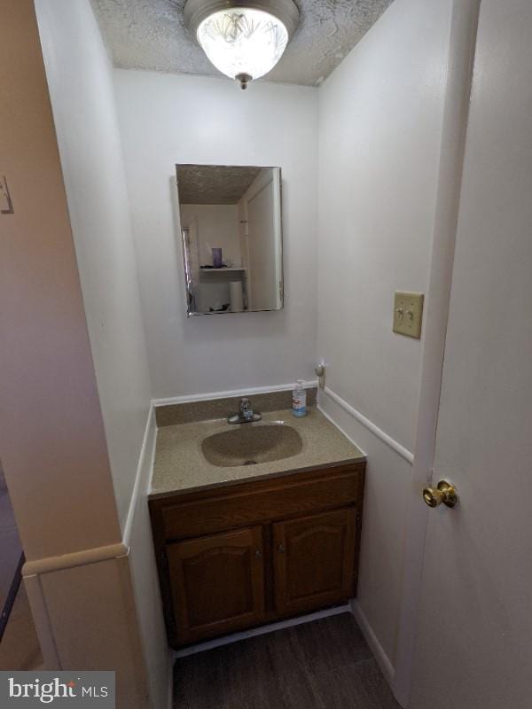 bathroom with vanity, wood-type flooring, and a textured ceiling