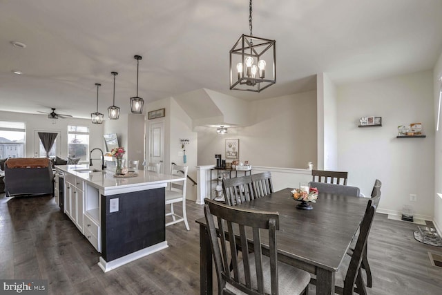 dining space with ceiling fan with notable chandelier, dark hardwood / wood-style floors, and sink