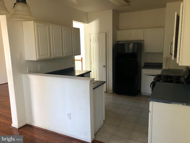 kitchen with black refrigerator, gas range, white cabinets, and light hardwood / wood-style flooring