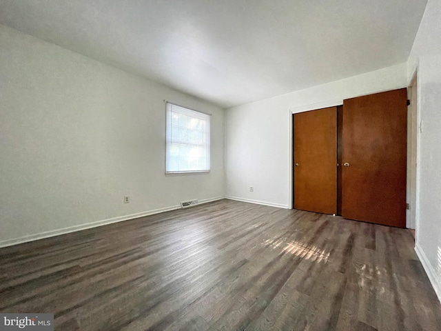 unfurnished bedroom with dark hardwood / wood-style floors and a closet