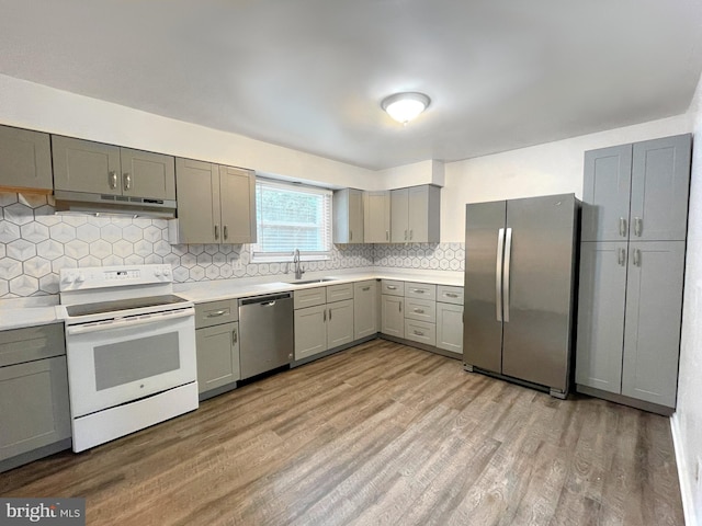 kitchen featuring appliances with stainless steel finishes, backsplash, sink, light hardwood / wood-style flooring, and gray cabinets