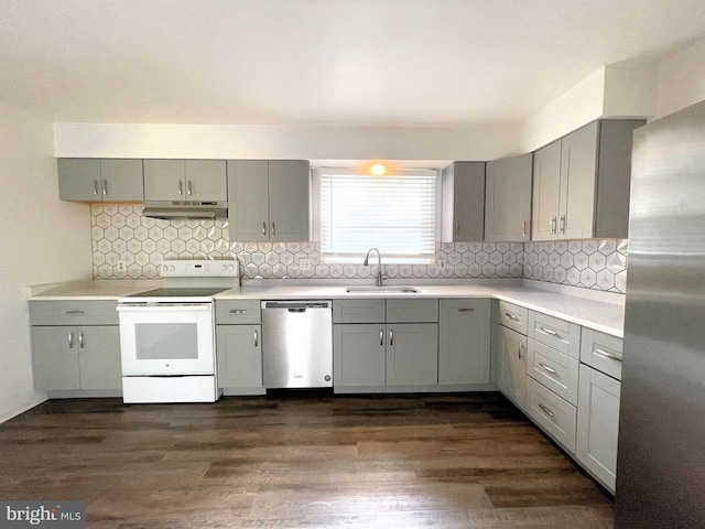 kitchen featuring appliances with stainless steel finishes, tasteful backsplash, dark wood-type flooring, and sink