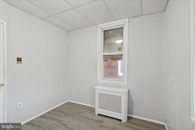 unfurnished room featuring radiator, a paneled ceiling, and light hardwood / wood-style flooring