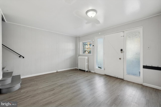 entrance foyer with wood walls, radiator heating unit, and hardwood / wood-style floors