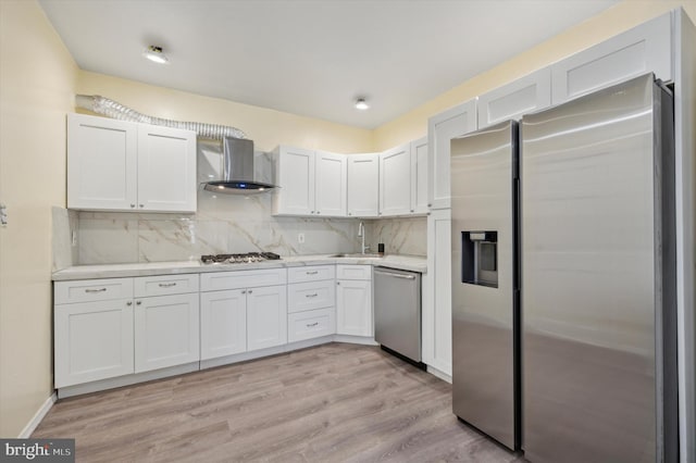 kitchen with white cabinets, stainless steel appliances, wall chimney exhaust hood, and sink