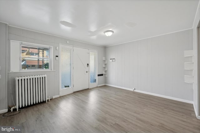 unfurnished room with radiator, wooden walls, and hardwood / wood-style flooring