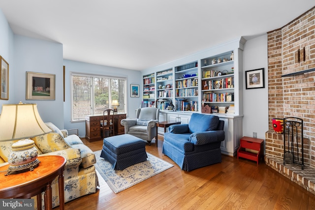 sitting room featuring a brick fireplace and wood finished floors