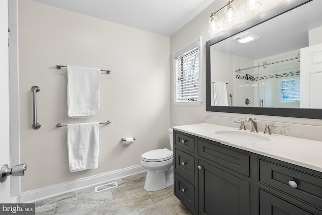 bathroom with visible vents, toilet, a shower with shower door, vanity, and baseboards