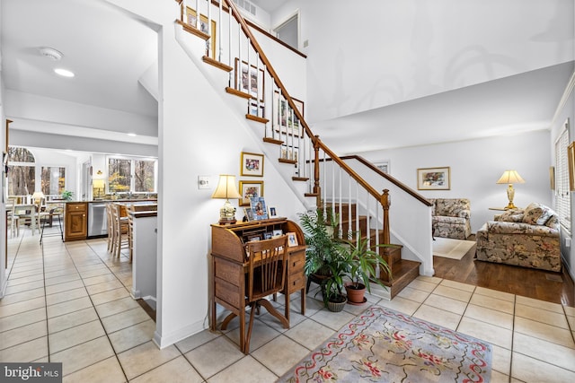 stairs featuring a high ceiling, baseboards, and tile patterned floors