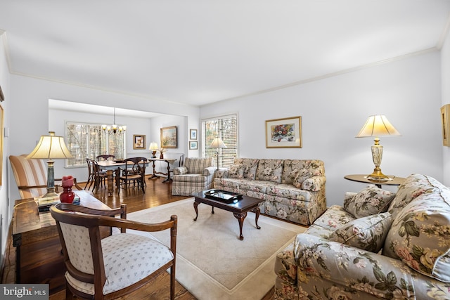 living area with a chandelier, crown molding, and wood finished floors