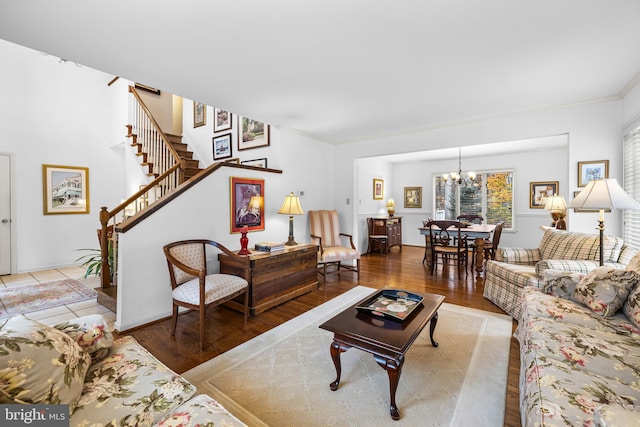 living room with ornamental molding, a notable chandelier, stairway, and wood finished floors