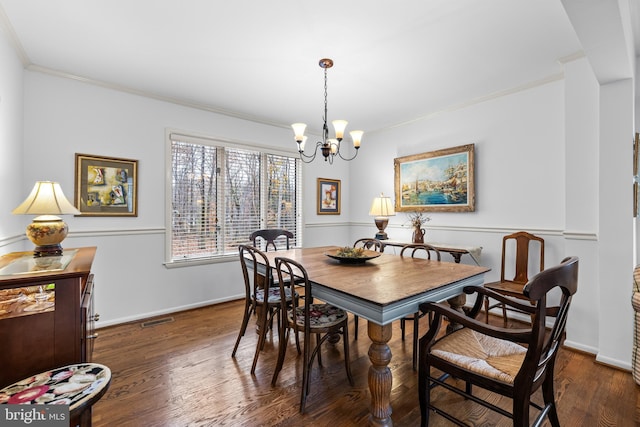 dining room featuring baseboards, visible vents, ornamental molding, wood finished floors, and a chandelier