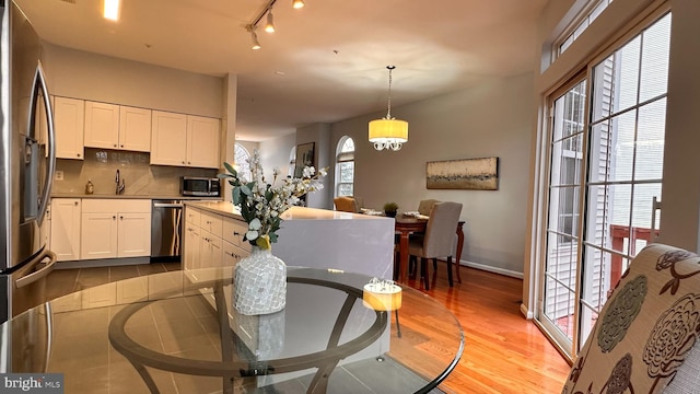 kitchen featuring decorative light fixtures, light wood-type flooring, stainless steel appliances, and white cabinetry