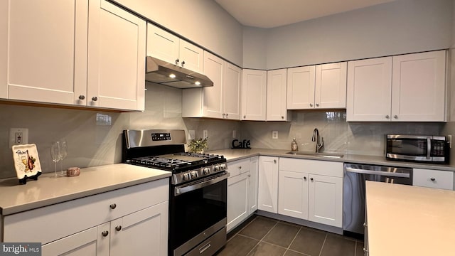 kitchen with appliances with stainless steel finishes, tasteful backsplash, sink, dark tile patterned flooring, and white cabinets