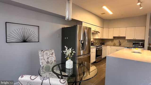 kitchen featuring white cabinetry, sink, dark tile patterned floors, decorative backsplash, and appliances with stainless steel finishes