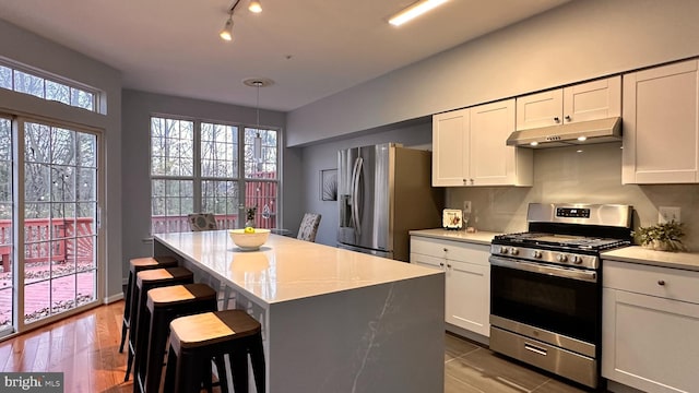 kitchen with pendant lighting, a breakfast bar, white cabinets, light hardwood / wood-style floors, and stainless steel appliances