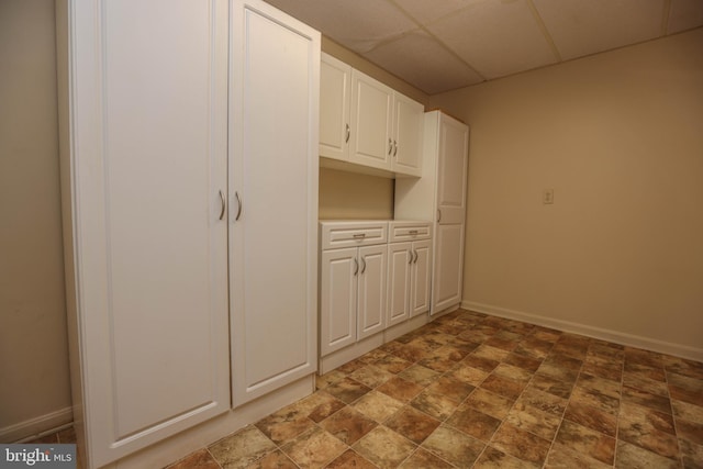 kitchen featuring a drop ceiling and white cabinetry