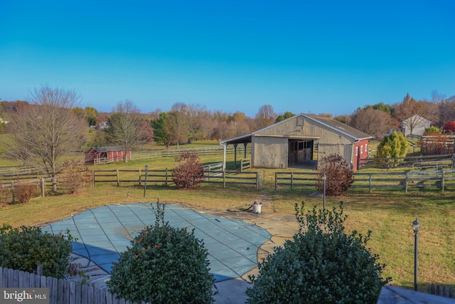 exterior space featuring an outbuilding, a rural view, and a lawn