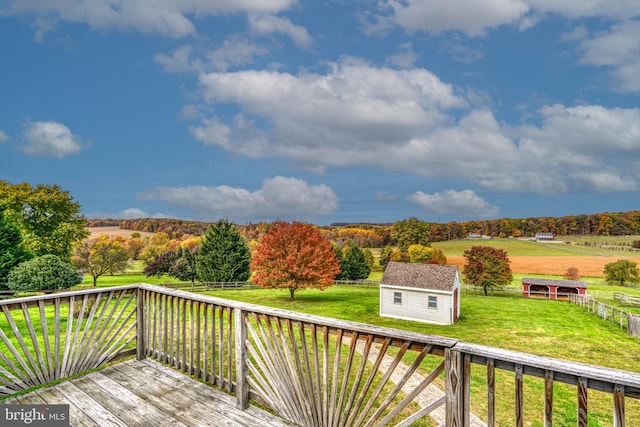 wooden deck with a yard, a rural view, and a storage shed