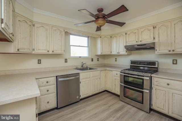 kitchen featuring sink, ceiling fan, light wood-type flooring, ornamental molding, and stainless steel appliances