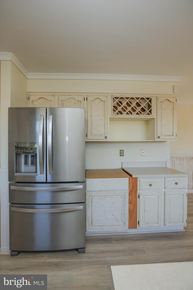 kitchen with stainless steel fridge, radiator heating unit, light hardwood / wood-style flooring, and ornamental molding