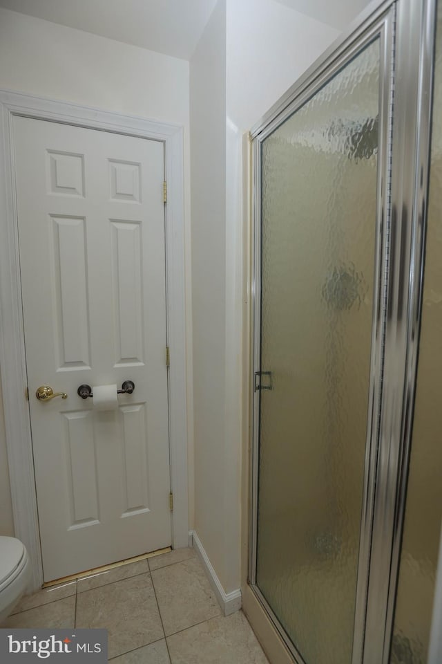 bathroom with tile patterned floors, toilet, and walk in shower