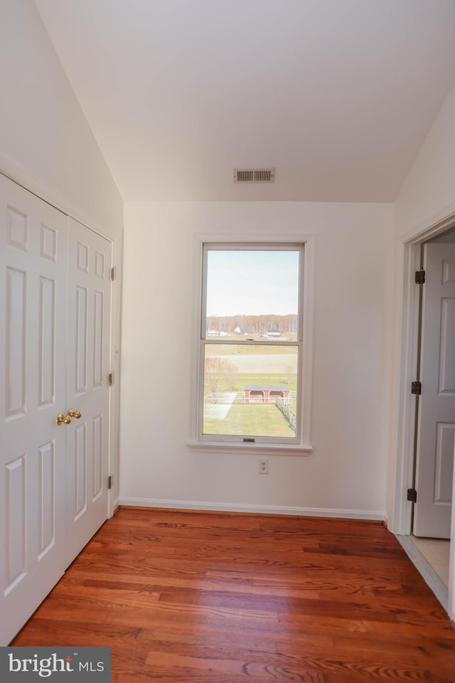 unfurnished bedroom with wood-type flooring, a closet, and lofted ceiling