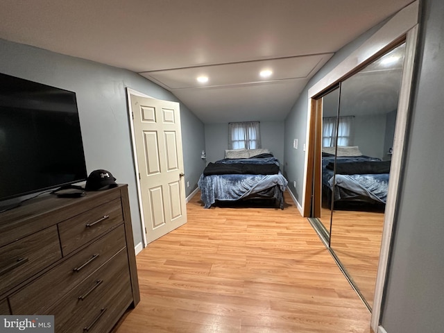 bedroom with a closet, light hardwood / wood-style floors, and lofted ceiling