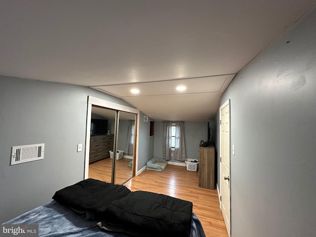 bedroom featuring light hardwood / wood-style floors, a closet, and vaulted ceiling