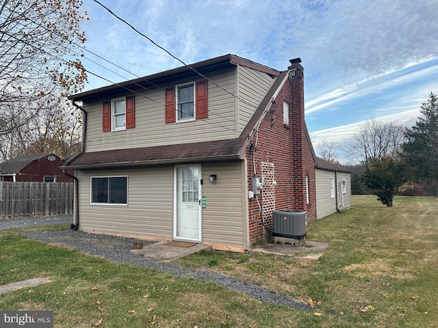 rear view of house featuring a yard and central AC unit