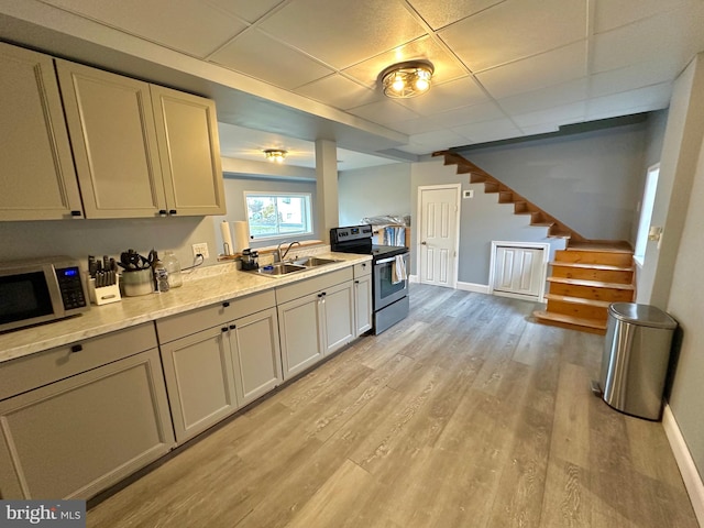 kitchen featuring light stone countertops, a paneled ceiling, stainless steel appliances, sink, and light hardwood / wood-style floors