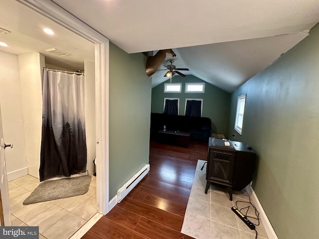 corridor with hardwood / wood-style flooring, baseboard heating, and vaulted ceiling