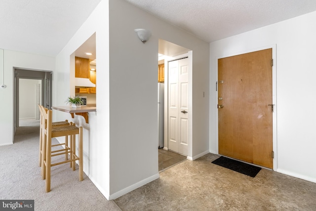 foyer featuring light colored carpet and a textured ceiling