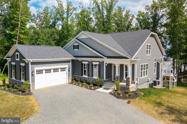 craftsman inspired home featuring a porch, cooling unit, a front yard, and a garage