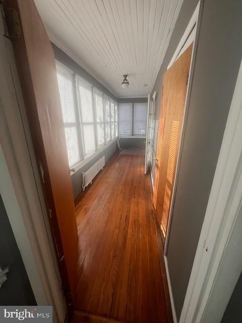 hallway with radiator heating unit, wood ceiling, and hardwood / wood-style floors