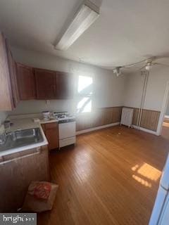 kitchen with hardwood / wood-style floors, white stove, ceiling fan, and sink