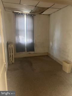 spare room with radiator heating unit and a drop ceiling