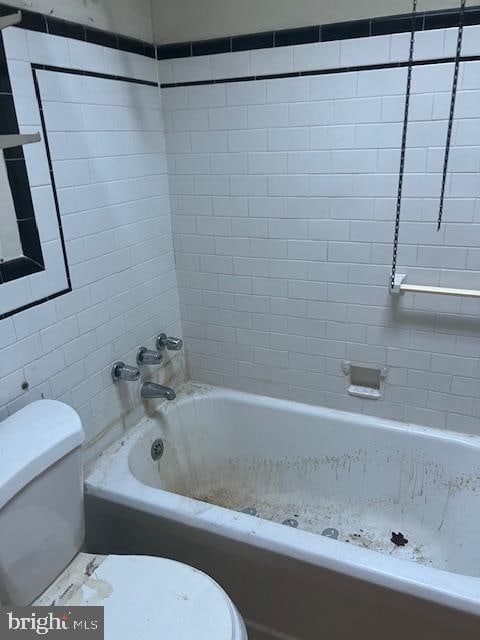 bathroom featuring toilet and tiled shower / bath