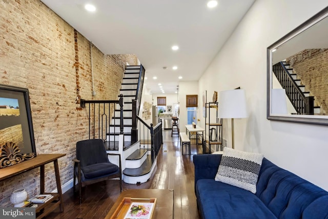 living room with dark hardwood / wood-style floors and brick wall