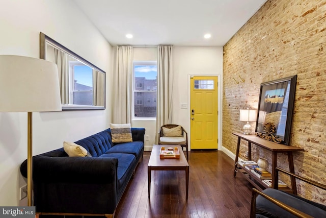 living room featuring brick wall and dark hardwood / wood-style flooring