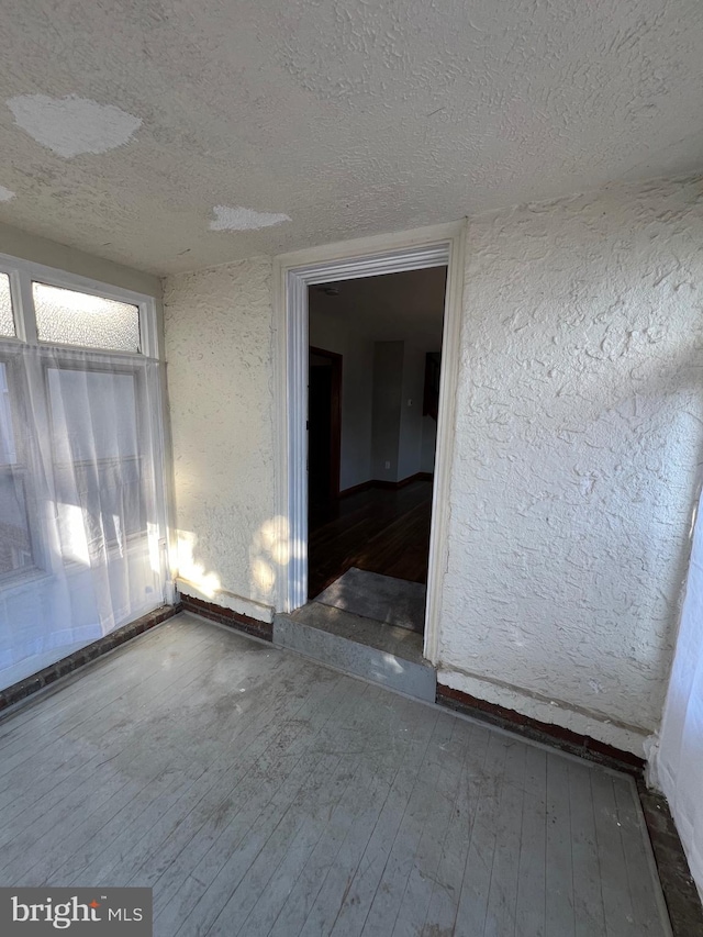 empty room with wood-type flooring and a textured ceiling