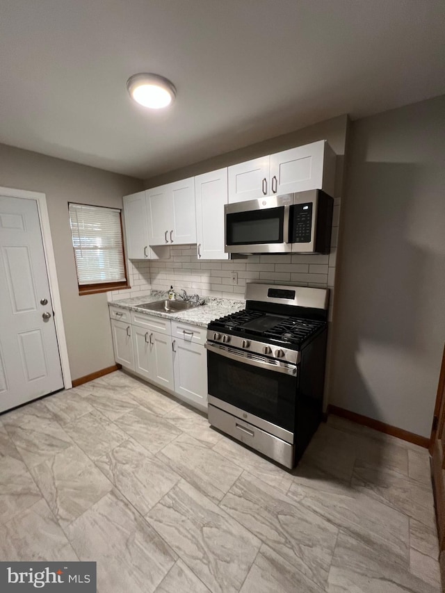 kitchen with white cabinets, sink, appliances with stainless steel finishes, and tasteful backsplash