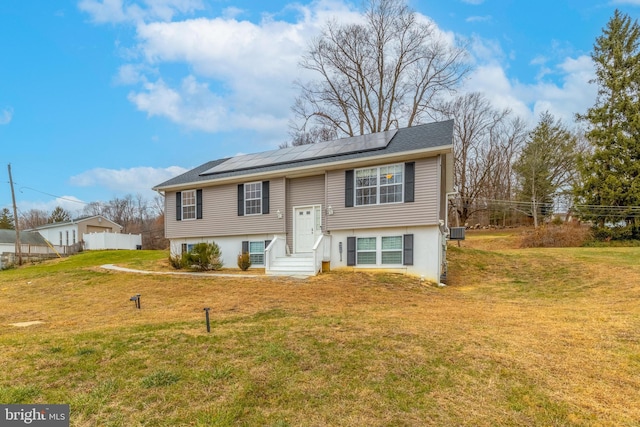 split foyer home with central AC, a front lawn, and solar panels