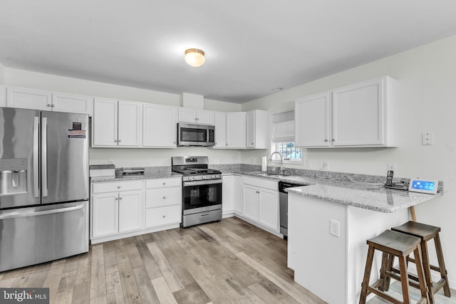 kitchen featuring kitchen peninsula, stainless steel appliances, white cabinets, and sink