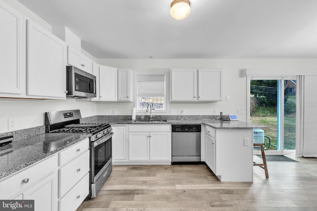 kitchen featuring white cabinets, dark stone counters, and appliances with stainless steel finishes