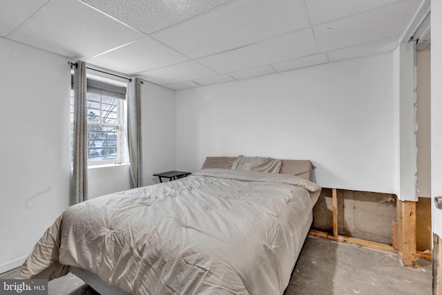 bedroom with a drop ceiling and concrete floors