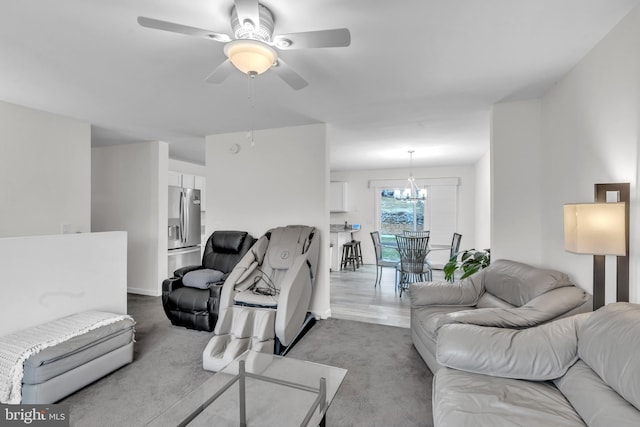 carpeted living room featuring ceiling fan with notable chandelier