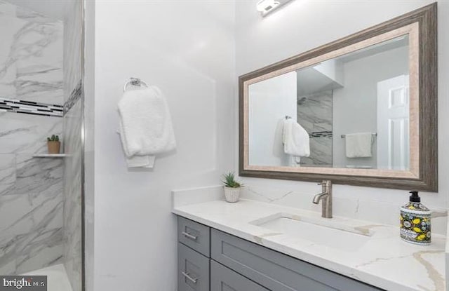 bathroom featuring a tile shower and vanity