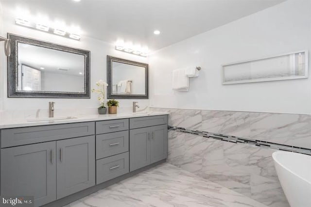 bathroom with vanity, a bathtub, and tile walls