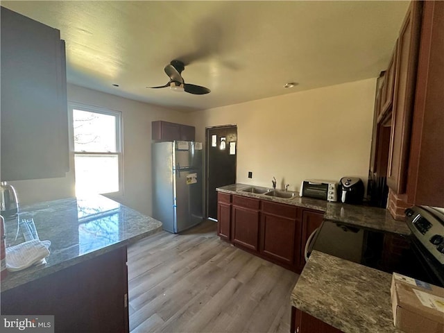 kitchen featuring ceiling fan, sink, stainless steel appliances, and light wood-type flooring